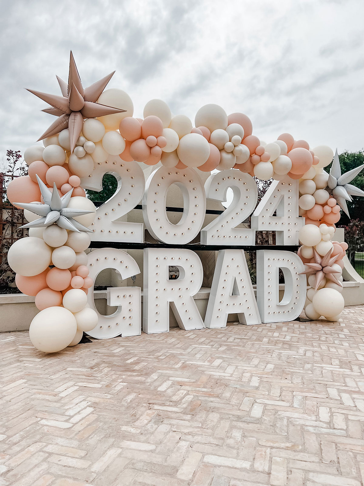 2024 GRAD — graduation balloon garland with blush, white, and peach accents