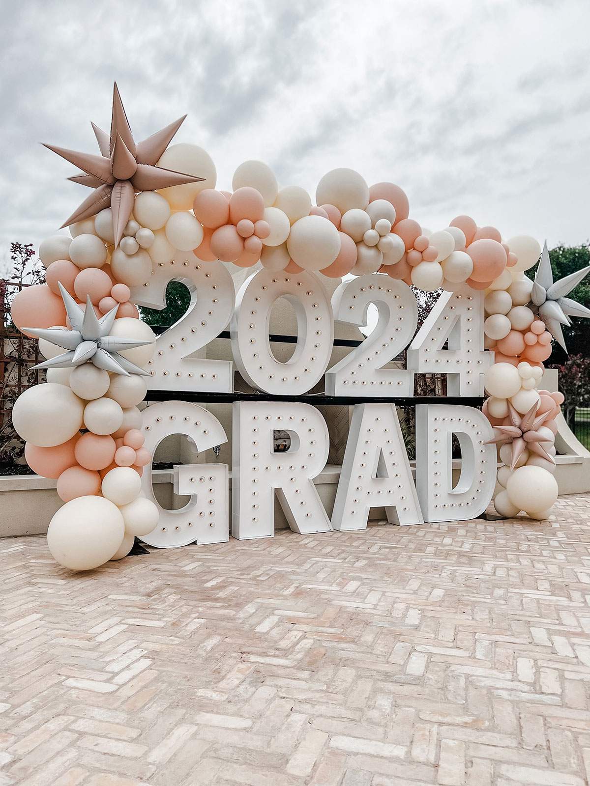 2024 GRAD — graduation balloon garland with blush, white, and peach accents